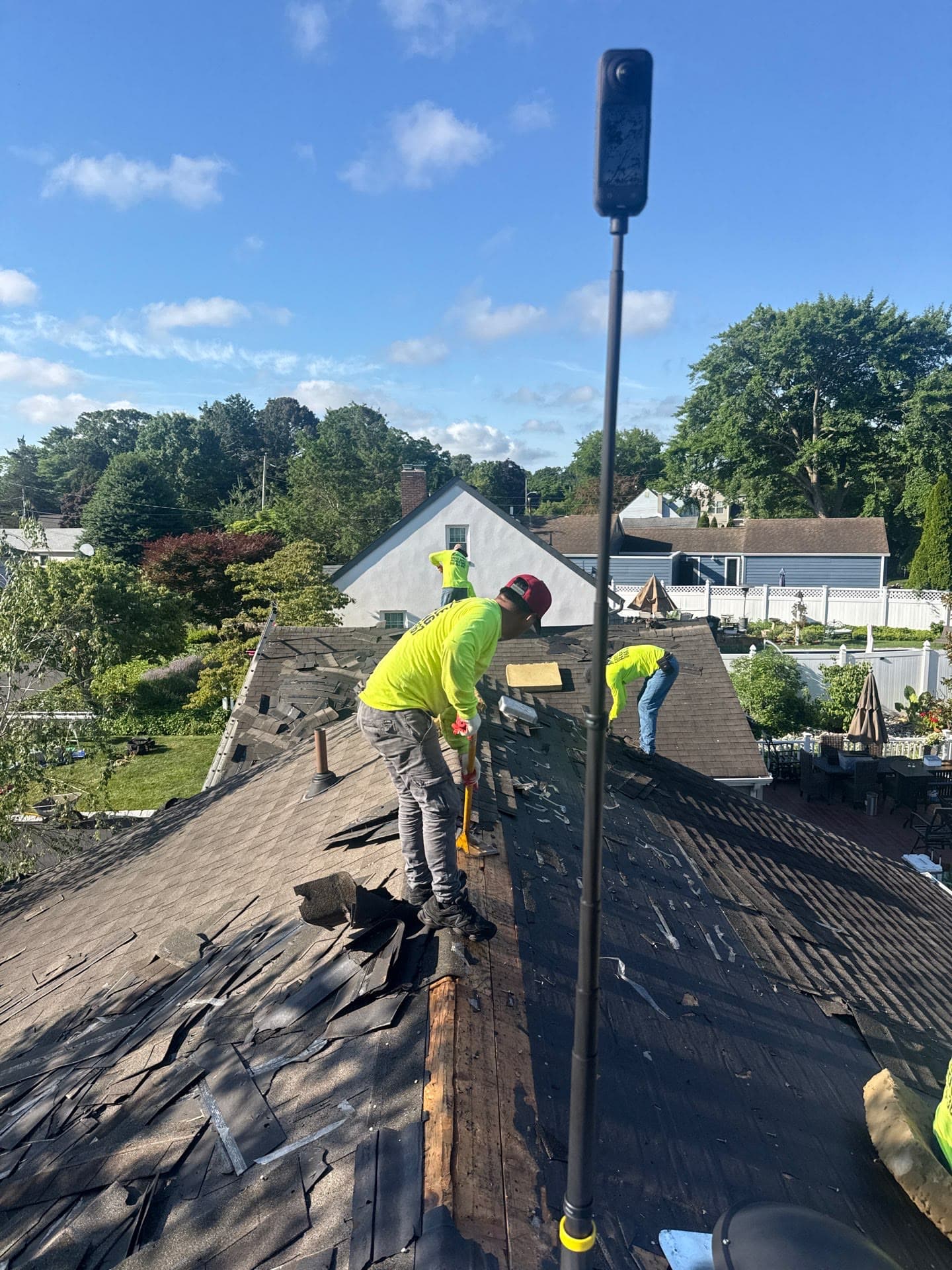 Two workers tearing off, blue sky — Green Apple Roofing, New Jersey