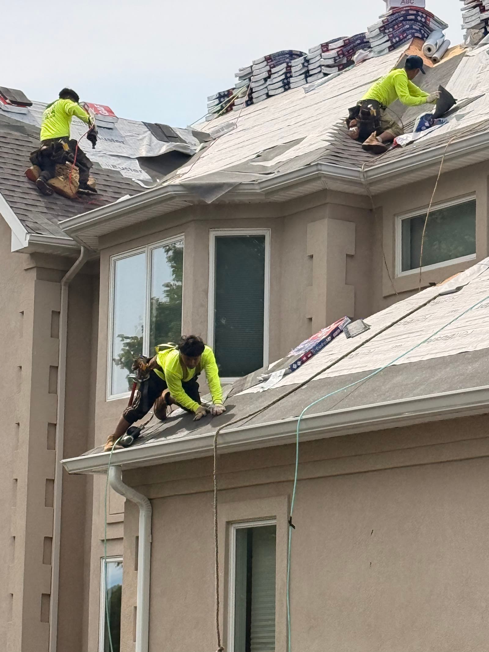 Crew in vests installing shingles, stucco home — Green Apple Roofing, New Jersey