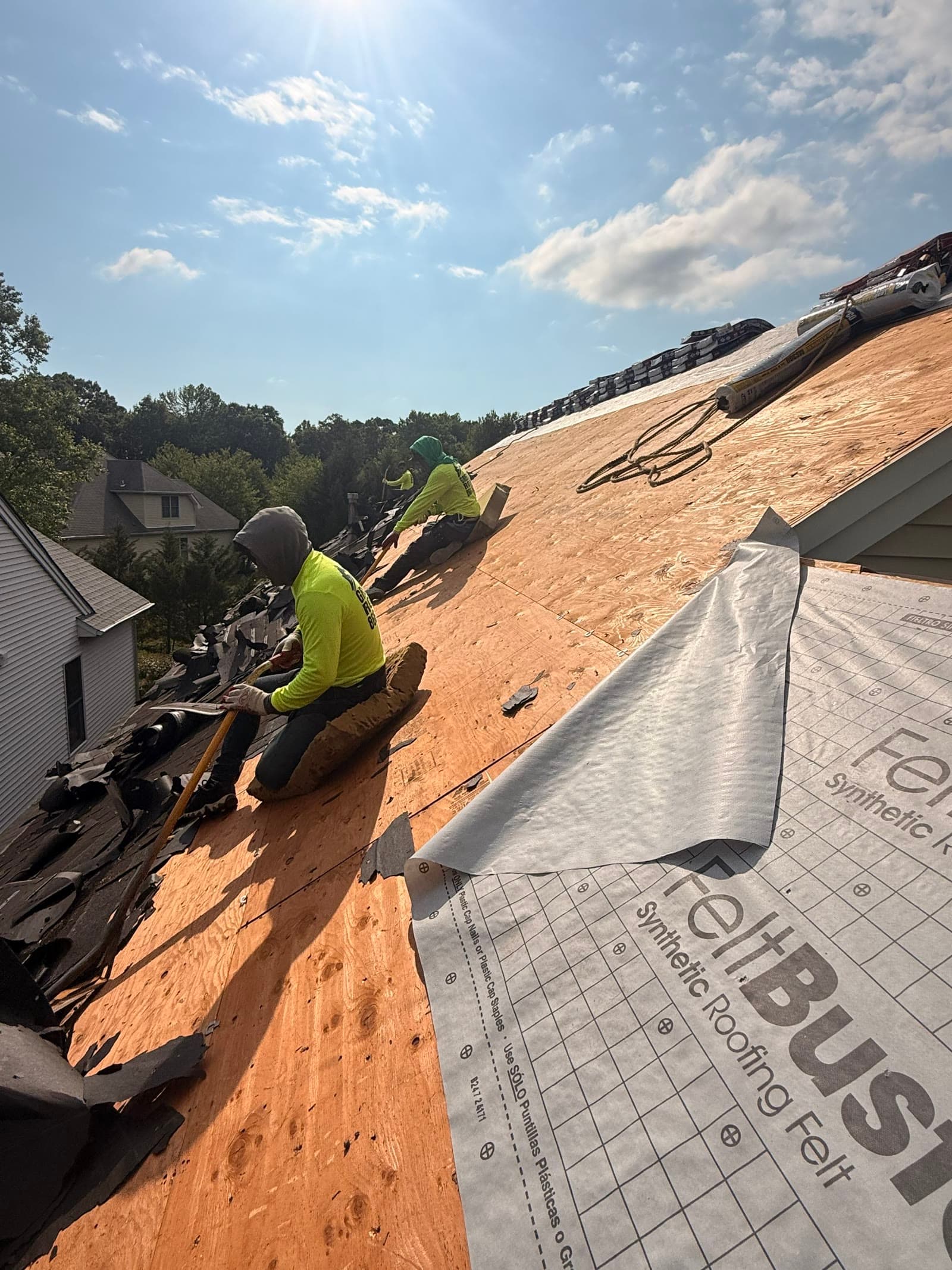 A roofer on sunlit decking with a roll of underlayment — Green Apple Roofing, New Jersey