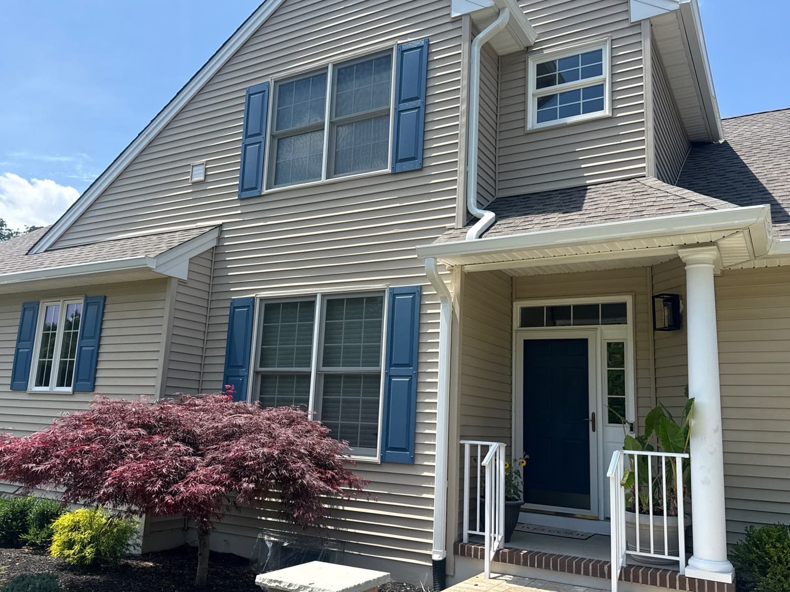 Two-story home with tan siding, blue shutters and a porch — Green Apple Roofing, New Jersey