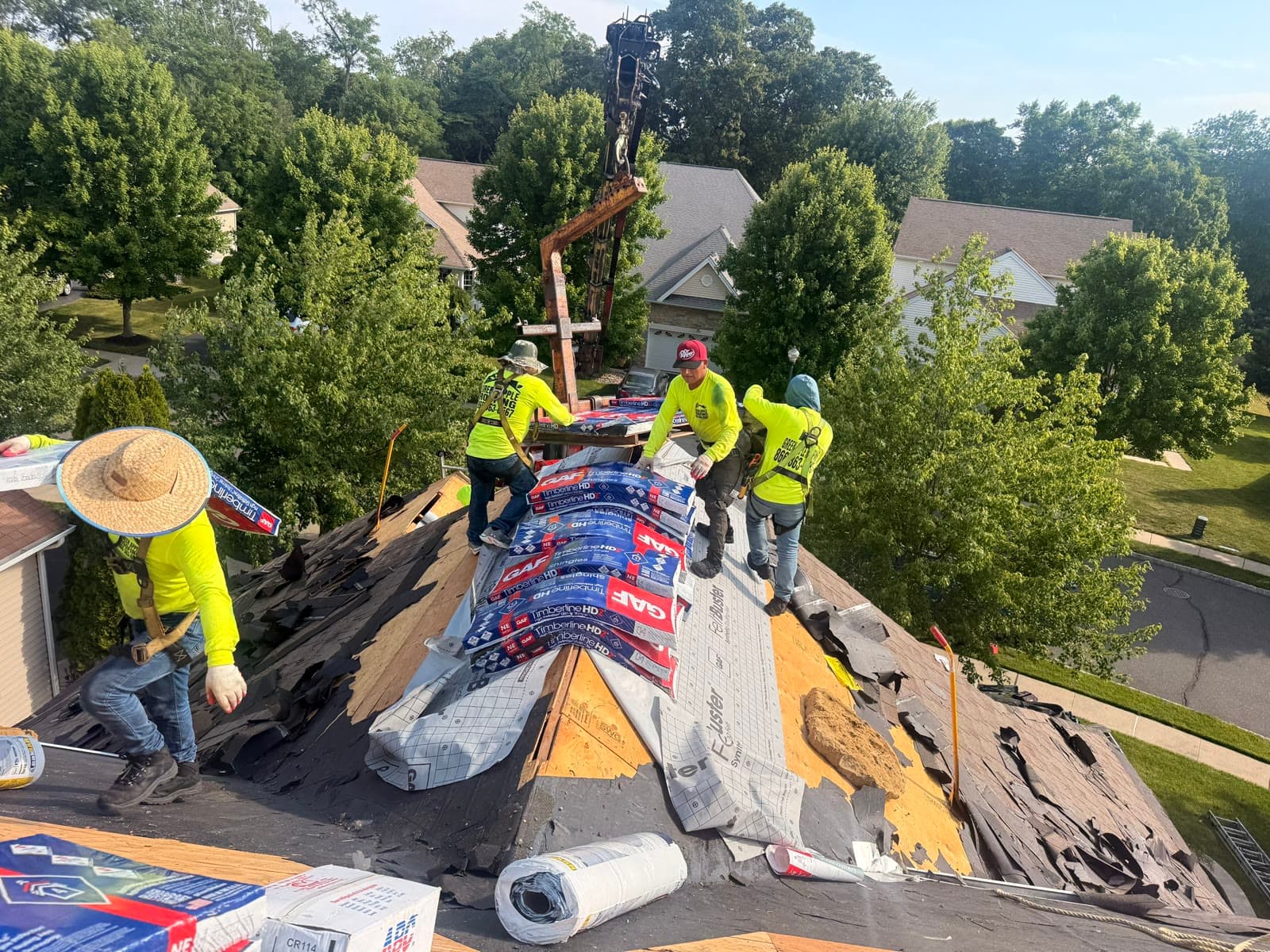 A crew loading shingle bundles onto a roof by crane — Green Apple Roofing, New Jersey