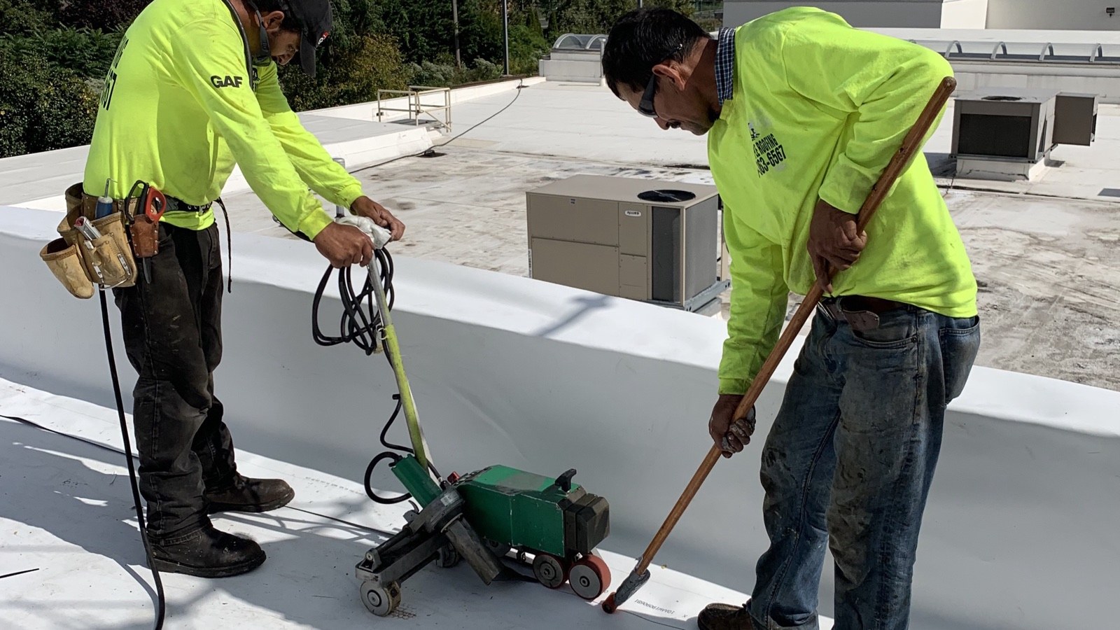 Green Apple Roofing crew hot-air welding a white TPO membrane seam on a commercial flat roof in New Jersey