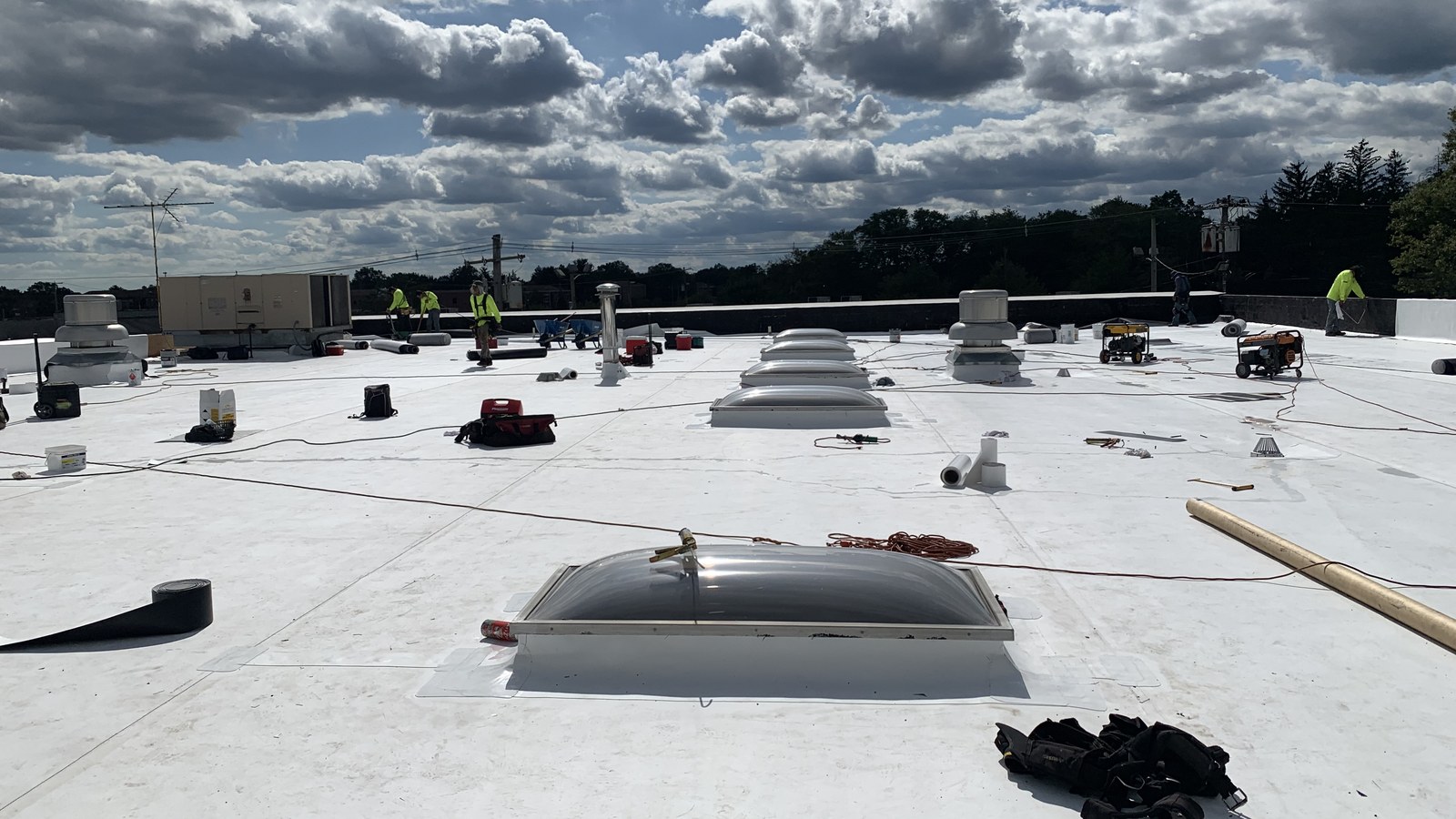A wide white TPO commercial roof in New Jersey with skylights, curbs, vents and roof drains visible — the surface a commercial roof inspection walks