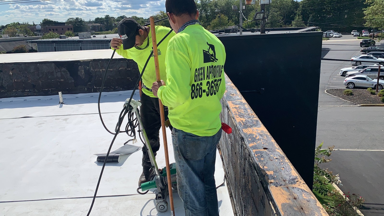 A branded Green Apple Roofing crew working on a white TPO commercial roof in New Jersey