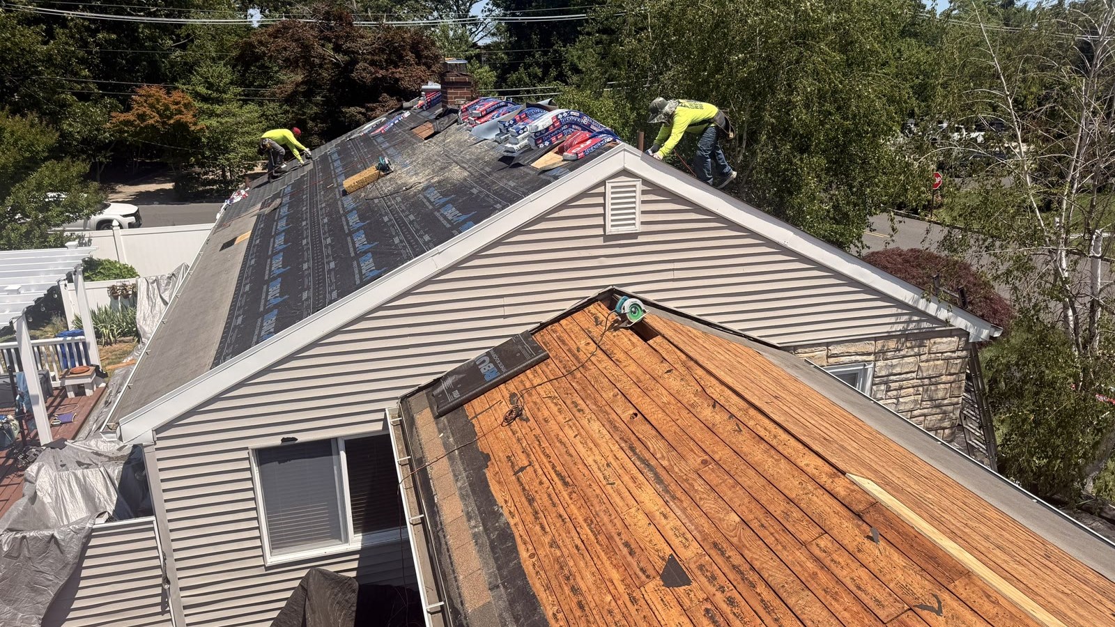A Green Apple Roofing crew inspecting a New Jersey roof with the old shingles off, showing the wood decking underneath