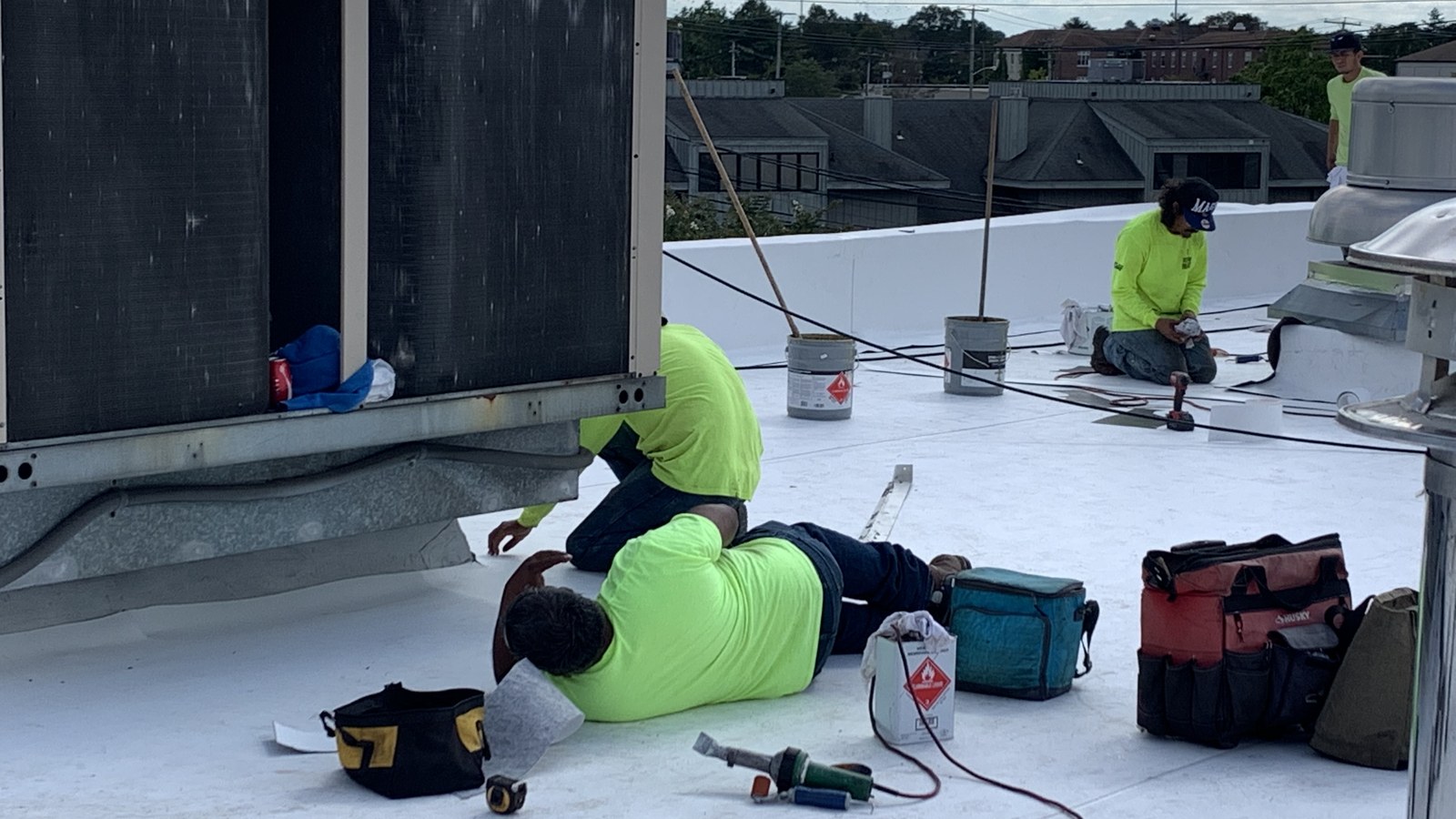 A Green Apple Roofing crew working at a rooftop HVAC curb on a New Jersey commercial flat roof — the kind of detail an emergency leak call traces back to