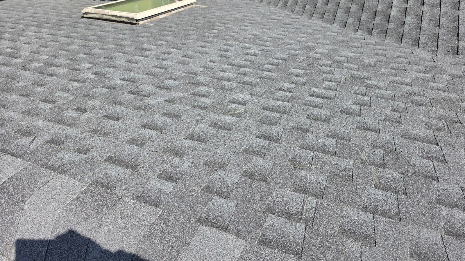 A skylight set into a finished gray asphalt shingle roof on a New Jersey home, installed by Green Apple Roofing