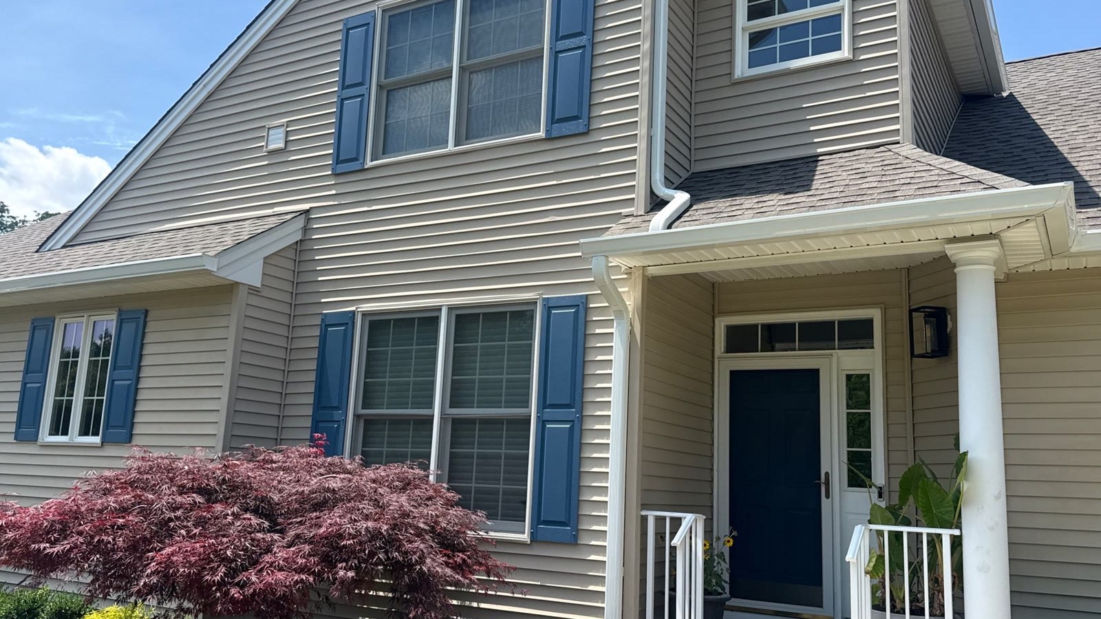 A New Jersey home with new tan lap siding, blue shutters, and white trim installed by Green Apple Roofing